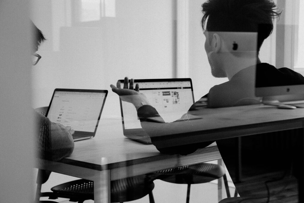 two people in front of two separate laptops having a discussion
